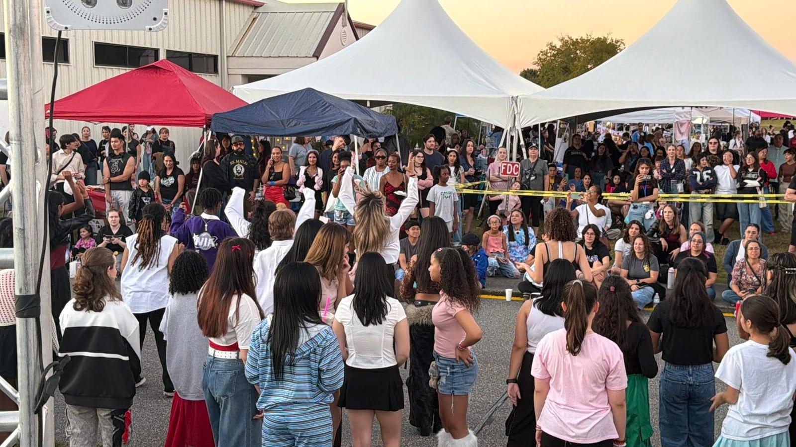 A packed crowd between the tents in the late afternoon