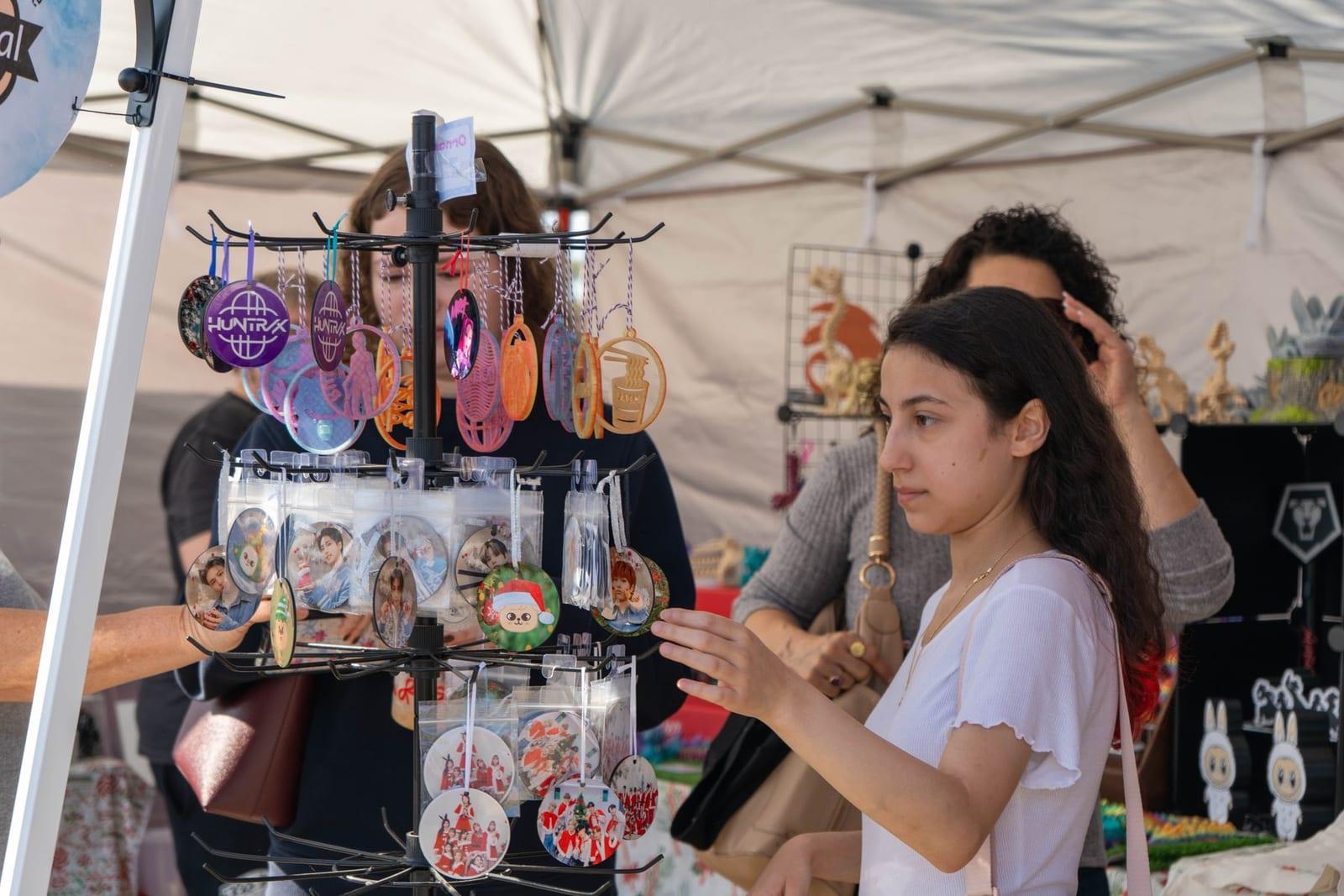 A visitor browsing keychains and pins at a vendor stall
