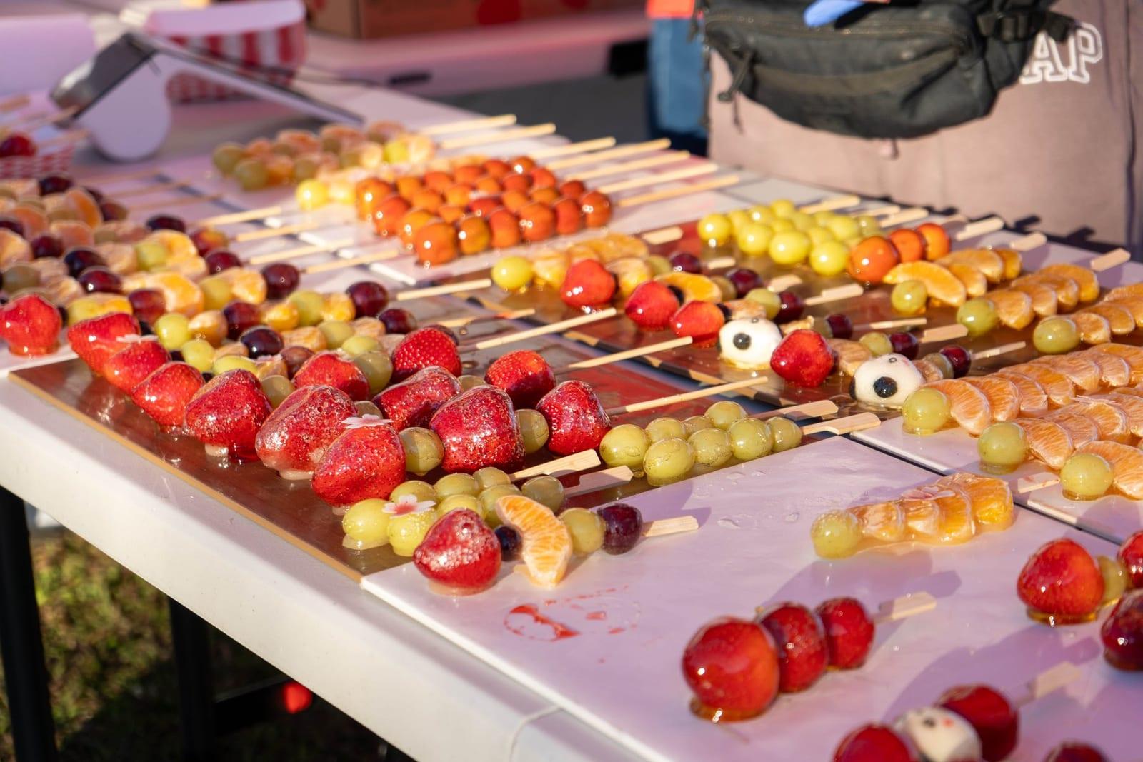 Trays of tanghulu — candied strawberries, grapes and mandarins on skewers